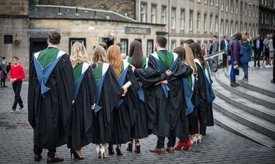 A row of 6Ͽ graduands standing in a row wearing their gowns outside Usher Hall